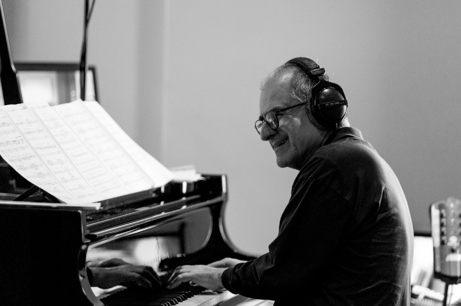 ENRICO PIERANUNZI in una foto in bianco e nero, cuffie in testa, intento a suonare il pianoforte