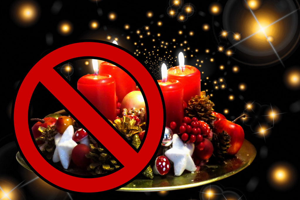 Pranzo di natale - delle candele natalizie su un vassoio con stelle bianche e pigne rosse e sulla sinistra il simbolo del divieto