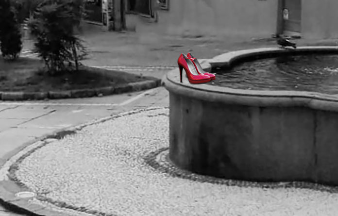 Moncalieri e Rosso Indelebile, nella foto delle scarpette rosse con il tacco a spillo appoggiate sul brodo della fontana della piazza di Moncalieri