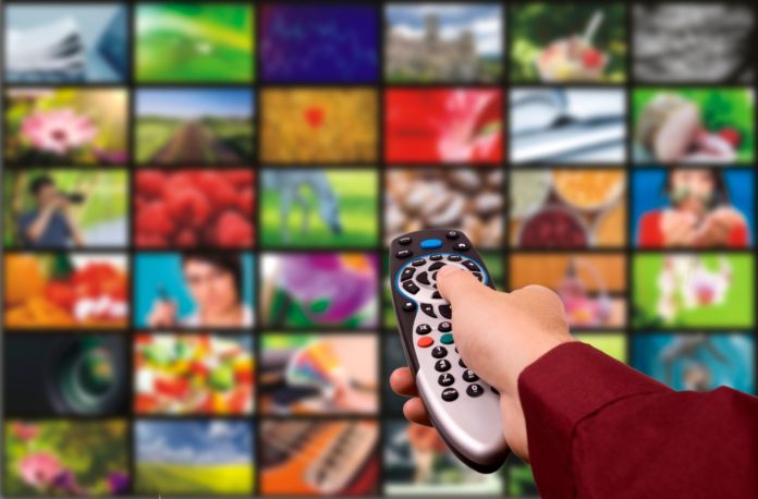 Tv on demand con uno schermo con mille immagini e una mano con un telecomando di fronte