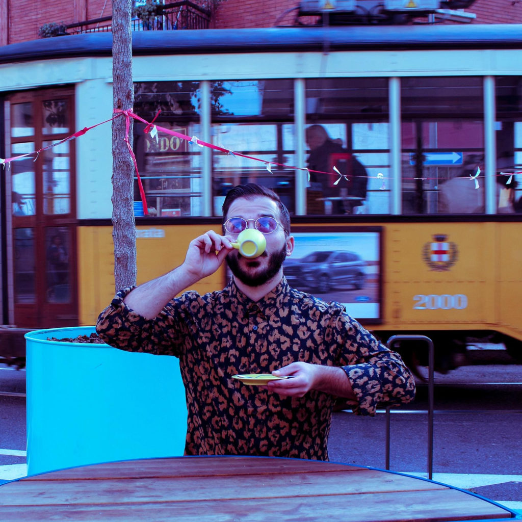 gabriele slep à il cantautore seduto ad un tavoloino, intento a sorseggiare una tazzina di caffè, alle spalle un tram giallo