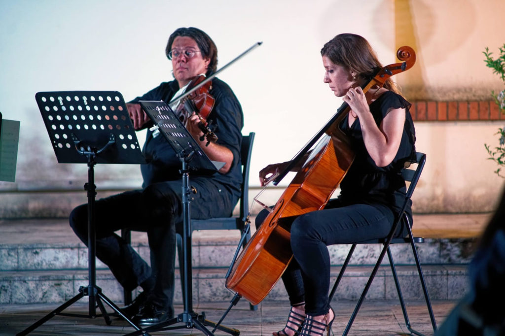 Morian Taddei e Orchesta Italiana del Cinema mentre suona il violino e vicino a lui una musicista con un violoncello