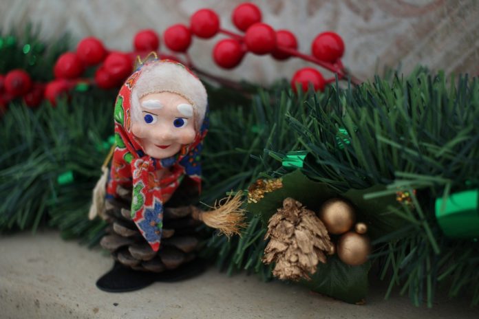 la befana con foulard e stracci con dell agrifoglio vicino