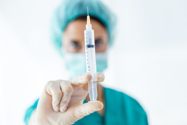 piano vaccini covid-19 un medico infila una siringa in un boccettino di vaccino