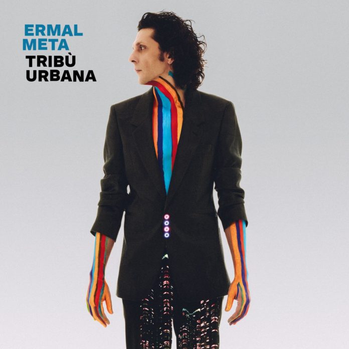 In foto la copertina dell'album di Ermal Meta Tribà urbana, l'artista è al centro di uno sfondo grigio, vestito di nero con delle strisce arcobaleno dipinte sul petto fino al collo, guada di lato verso sinistra, accanto il suo nome in azzurro e il titolo dell'album stampato in nero