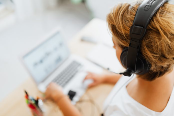 interviste ai tempi di lockdown - nella foto na donna con capelli biondi coriti e con una cuffia per ascoltare musica sugli orecchi, sta scrivendo sulla tastiera di un pc