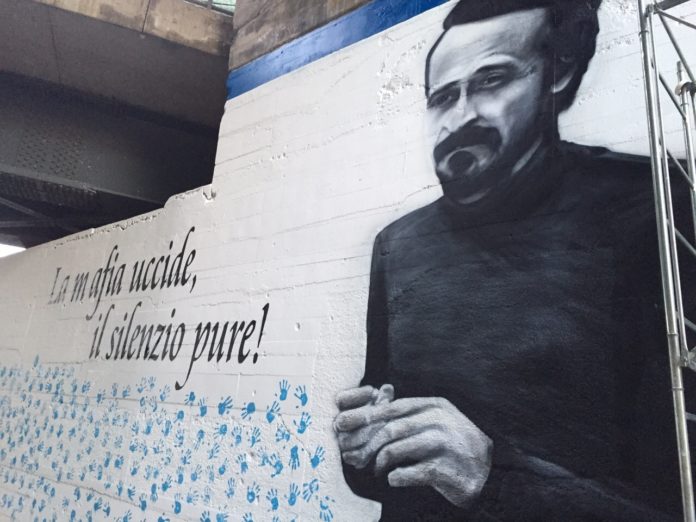 i cento passi - nella foto il murales dedicato a peppino impastato, . Su sfondo bianco la scritta 