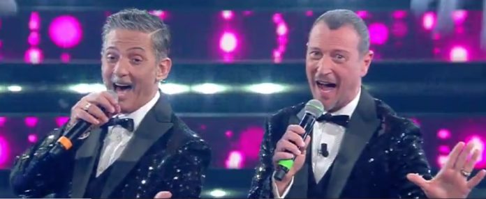 si può essere amici per sempre - Fiorello e Amadeus vestiti con smoking neri e pailettes cantano con microfono sul palco dell'ariston