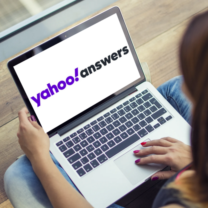Yahoo Answers scritto sullo schermo di computer poggiato sulle ginocchia di una ragazza