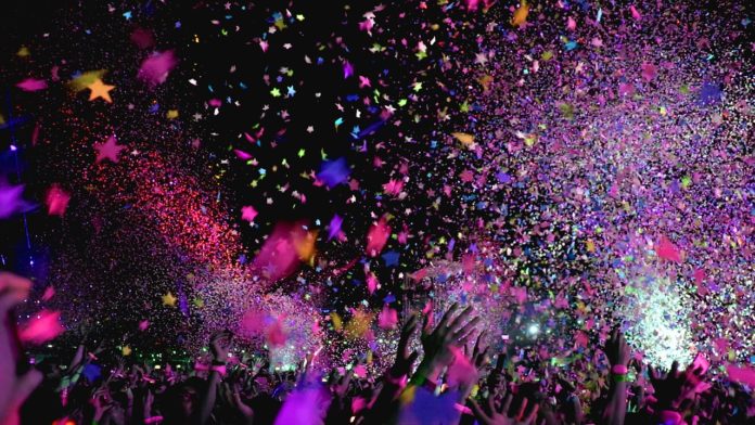 TOurDAYS nella foto un folla nel buio di un concerto con tanti coriandoli colorati che piovono su di loro