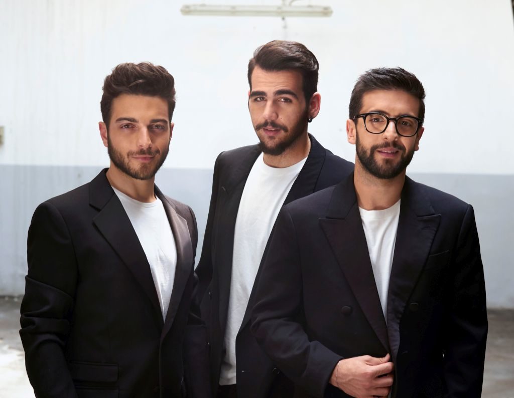 Il volo tre ragazzi giovani, tutti e tre con barba ben curata corta, capelli corti, sono vestiti con t shirt bianca e giacca smoking nera