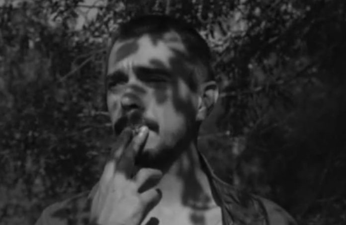 ultrà - pagano in una foto in bianco e nero, circondato dagli alberi, intento a fumare una sigaretta