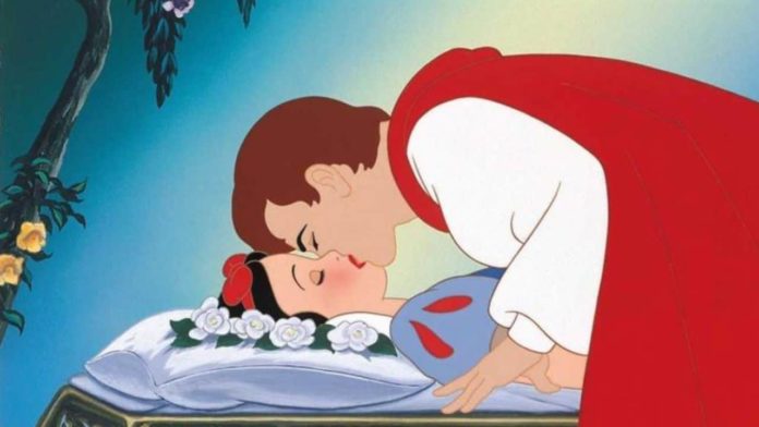 Biancaneve, bacio, principesse. La scena del bacio. Biancaneve dorme su un lettino bianco e un cuscino ricoperto di rose. Il principe indossa una camicia bianca e il mantello rosso, si china su di lei per baciarla.