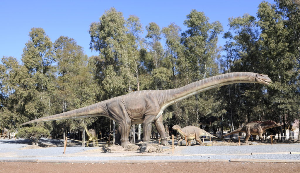 un branchiosauro con un collo molto lungo e lunga coda nel verde di un parco