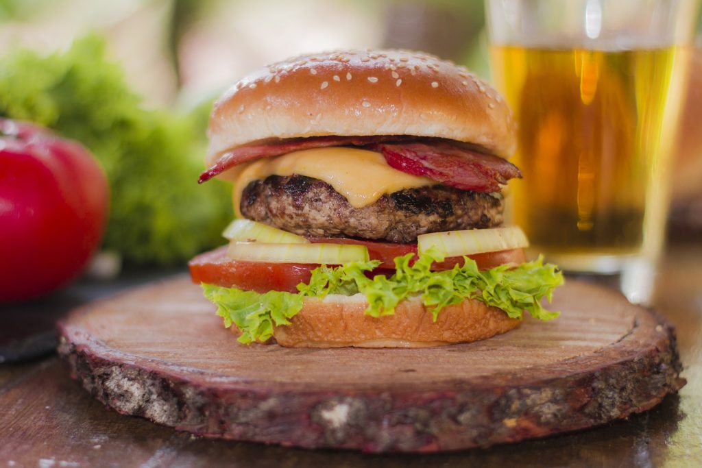 social e cibo - Un hamburgher con insalata, pomodoro, formaggio a fette e carne tra due fette rotonde di pane