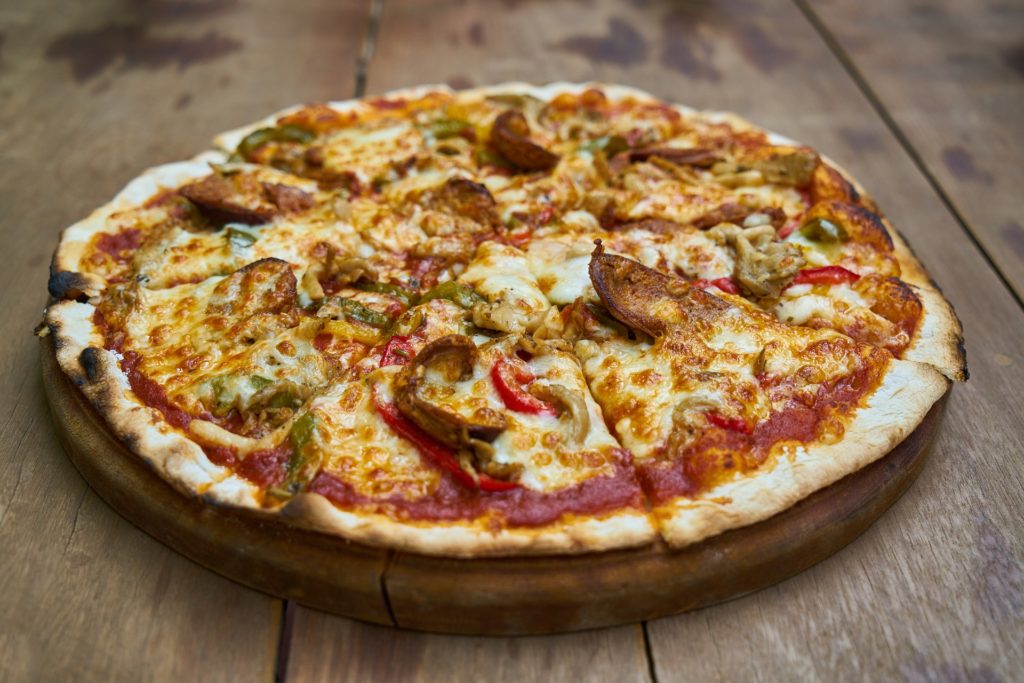 social e Food porn : una pizza appoggiata su un tagliere di legno, su un tavolo di legno
