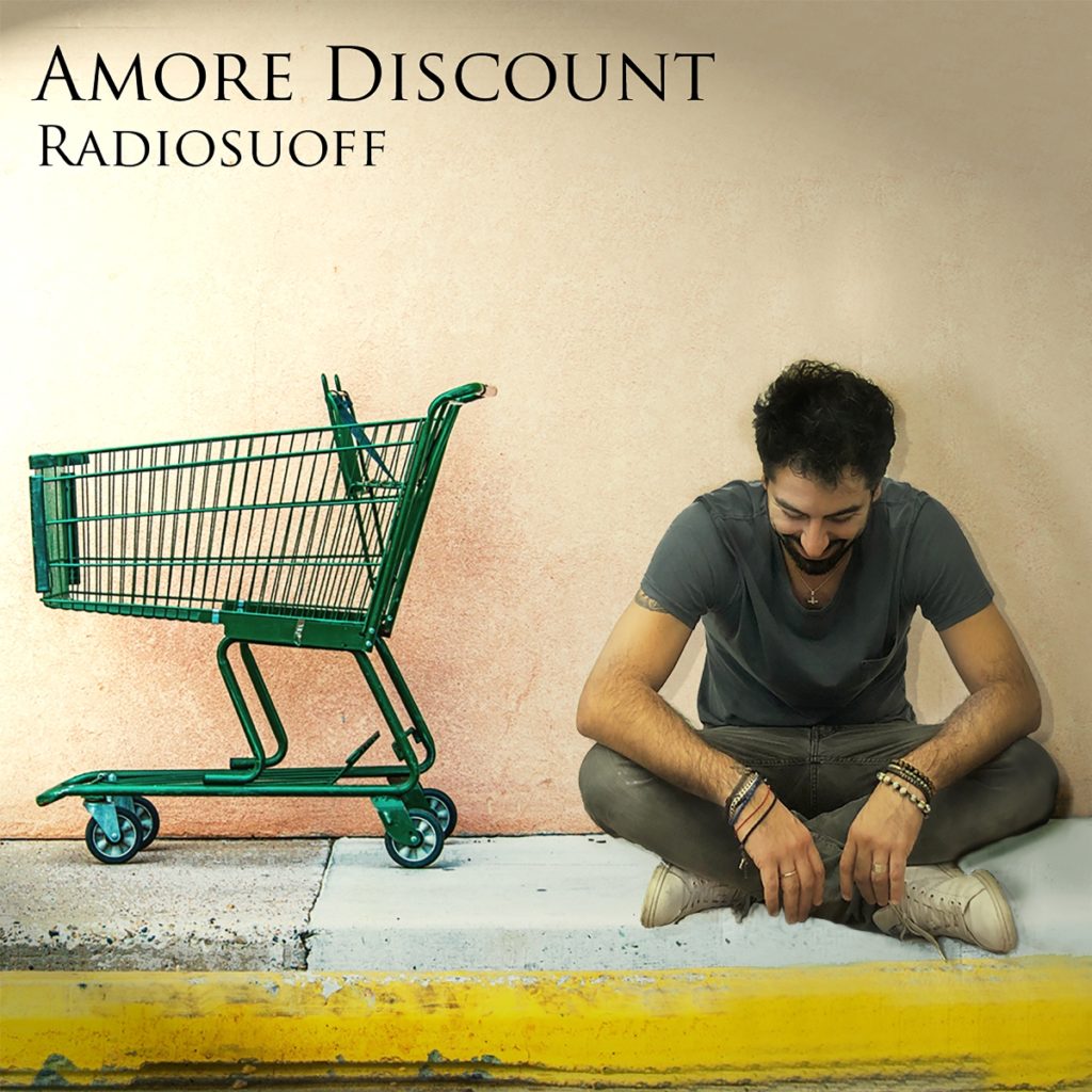 radiosuoff - la copertina di amore discount che vede il cantautore seduto a gambe incrociate, di fianco ad un carrello del supermercato