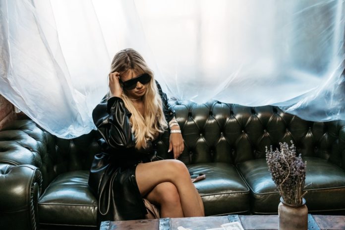 Natalia Moskal, ha una giacca nera, indossa gli occhiali da sole, seduta su un divano nero