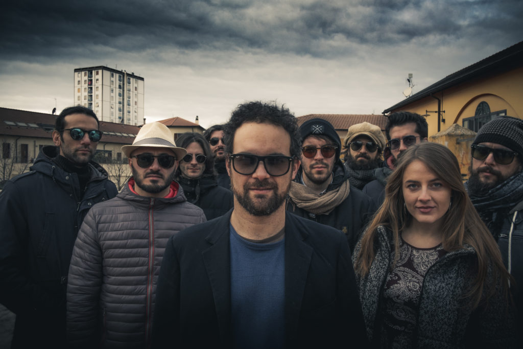 l'orchestra Magna in un afoto di gruppo all'aperto con dietro un cielo nuvoloso