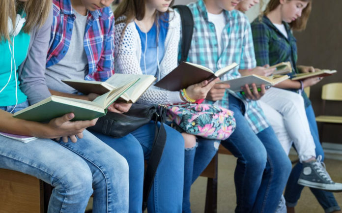baqndo per la lettura: nella foto degli studenti seduti su una panca, tutti stanno leggendo un libro