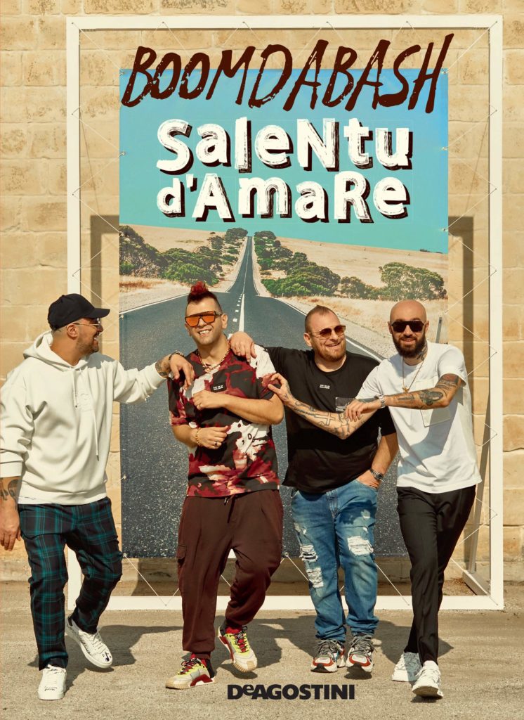 Salentu d'AmaRe - la copertina del libro, su sfondo beige, i quattro ragazzi della band vestiti con pantaloni di jeans , felpe e magliette soino davanti a una strada in mezzo alla sabbia e al verde