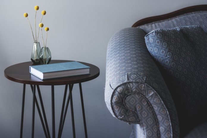 Mercato Immobiliare : nella foto un tavolino nero con gambe di ferroo, su cui appoggiano un libro e due vasetti con dei fiori finti, affianco al tavolino si vede il bracciolo di un divano blu a pallini