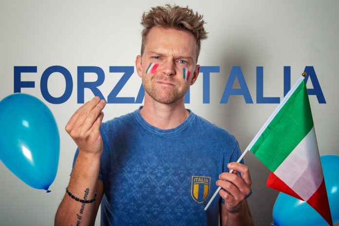 Mancini Azzurri - nella foto un tifoso della Naqzionale di calcio Italiana, con la maglia azzurra, in faccia ha disegnato il tricolore italiano, nella mano sinistra tiene la bandiera dell'Italia e con la mano destra fa il gesto di 