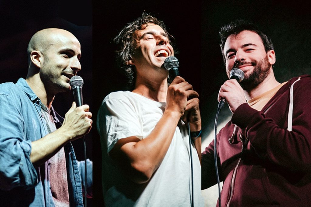 Altra Scena Péiombino Festival, nella foto Luca Ravenna e altri due artisti con microfono in mano, sorridono mentre si esibiscono. Quello sulla sinistra indossa camicia di jeans su una t shirt. E' calvo. Quello al centro indossa una t shirt bianca, mentre quello sulla destra ha barba e baffi neri e indossa una camicia rossa