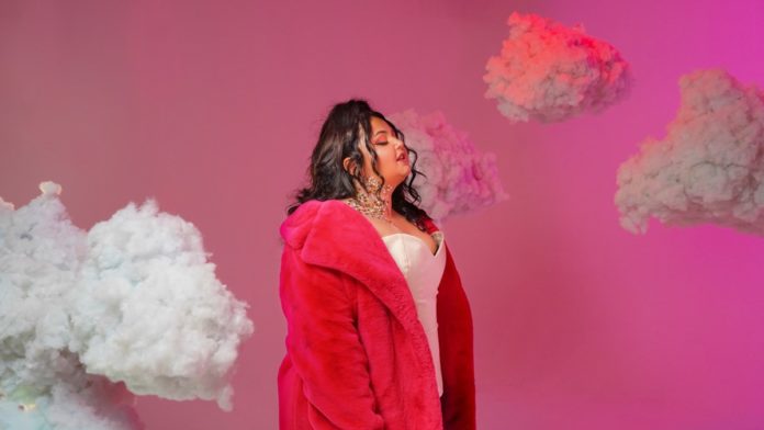 ratatà boom - raffy, che indossa una pelliccia rosa e un corpetto bianco, circondata da nuvole colorate, su sfondo fucsia