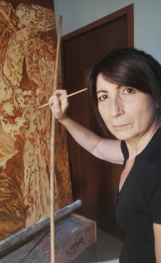 Nel regno della Surrealtà di Silvana Cimieri la pittrice al suo cavalletto con una tela di pareidolia. 