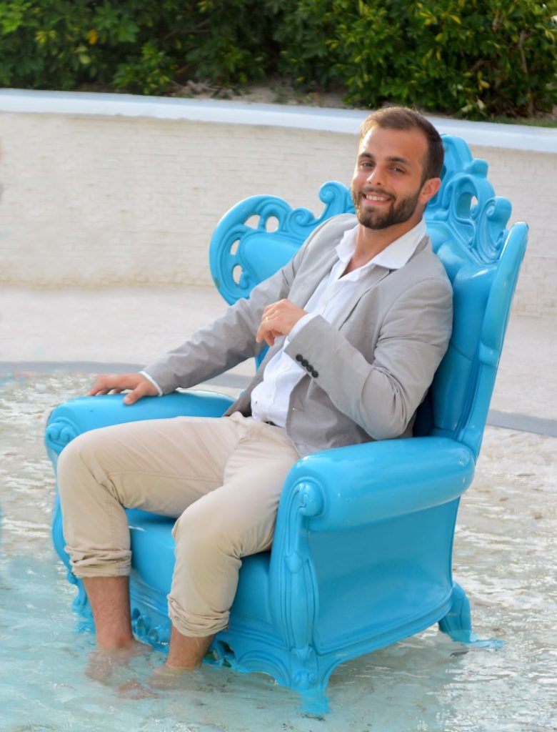 viaggiare - Paolo motta '900 vestito di chiaro, seduto su una poltrona azzurra, posizionata dentro una piscina