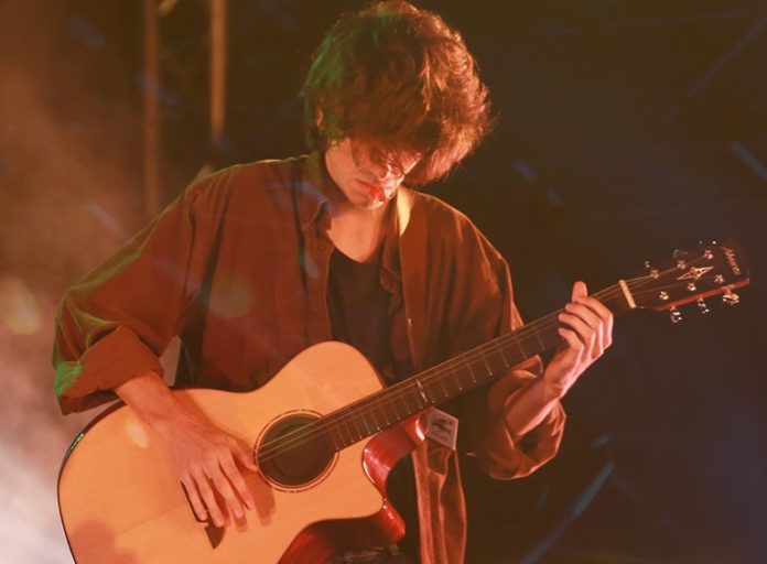 Una voce per l'Europa - la locandina con al centro un ragazzo con capelli lunghi vestito di beige, in piedi, suona la chitarra su un palco