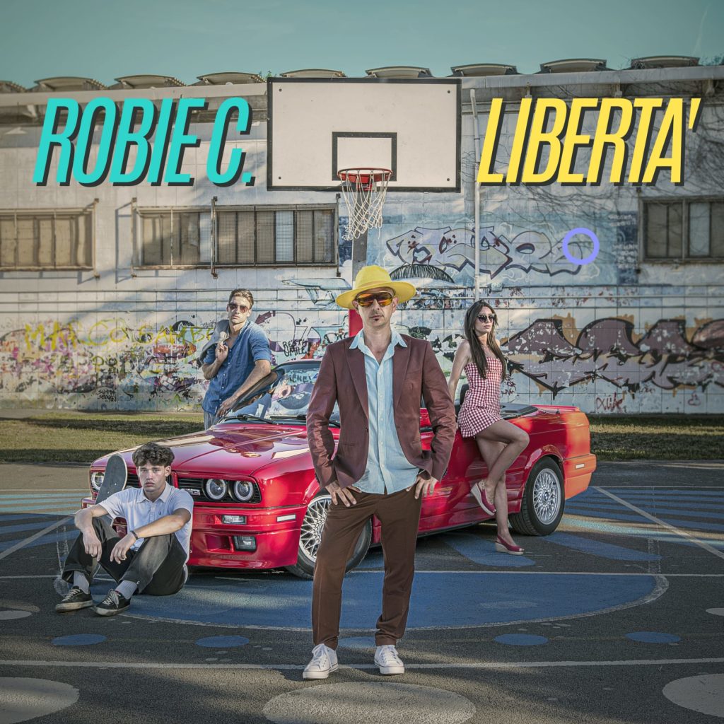 robie c. - la copertina del singolo libertà che lo ritrae in primo piano, con un abito marrone, davantia a una bmw rossa decapottabile