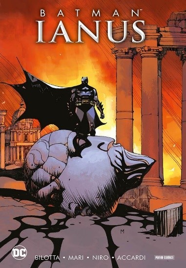 la copertina del fumetto storia Ianus con Batman con il mantello nero svolazzante, in piedi su un masso che cadendo ha crepato tutto l asfalto e dietro di lui due colonne con uno sfondo rosso e arancione giallo