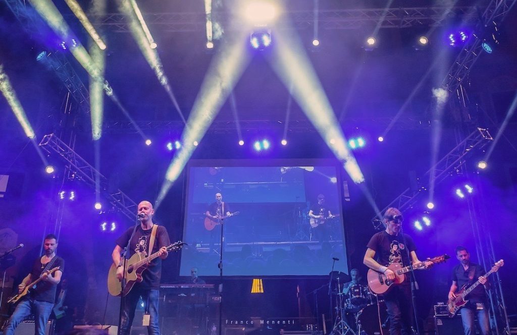 Mei 2021 - nella foto sul palco del mei la Rino Gaetano Band con luci biaanche su sfondo azzurro