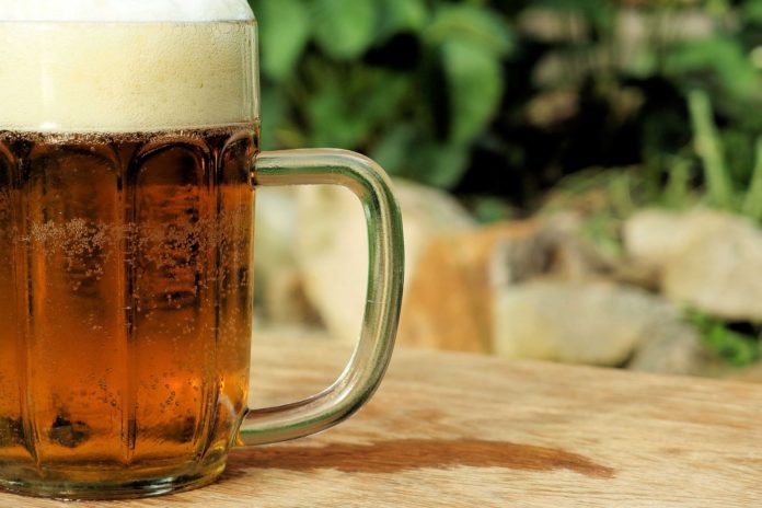 Oktober Fest unboccale di birra in primo piano con tanta schiuma bianca, appoggiato su un tavolo all'aperto