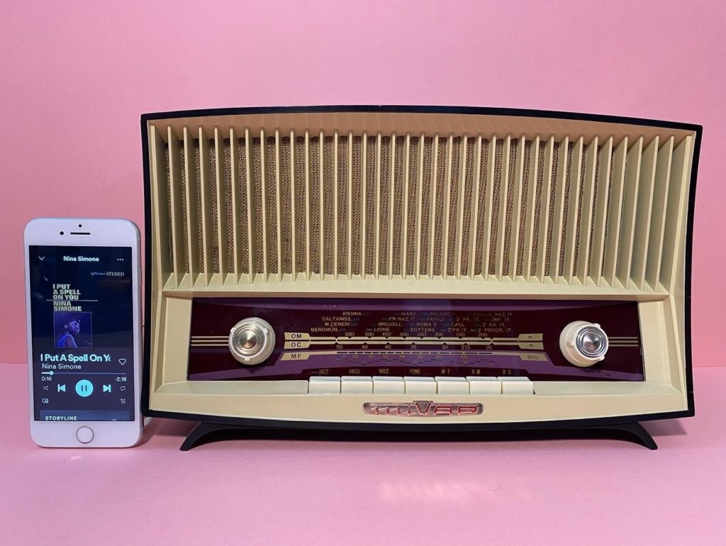 Vintage e rarità - una vecchia radio a transistor con due manopole, per la sintonizzazione e l audio, vicino a un telefonino di nuova generazione