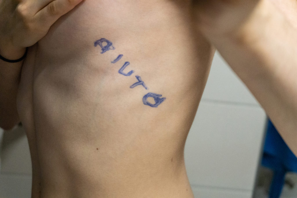 Giovani e disturbi alimentari - il fianco nudo di un corpo maschile con la scritta "aiuto" sulle costole 