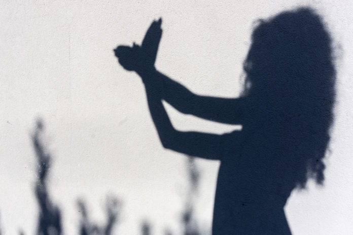 Guiovani e disturbi alimentari - in un afoto in bianco e nero si vede l'ombra di una donna che fa le ombre cinesi con le mani formando una colomba