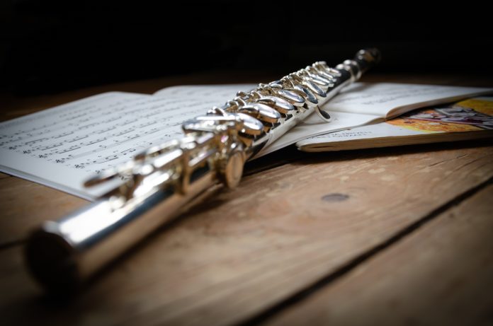 Flautissimo - un flauto appoggiato su un pentagramma musicale su un tavolo di legno