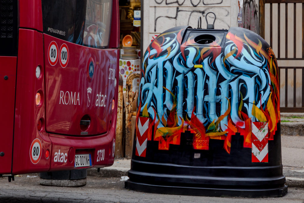Inferno di Dante - Una campana del vetro disegnata con street art vicino al retro di un pulmann rosso della città di Roma