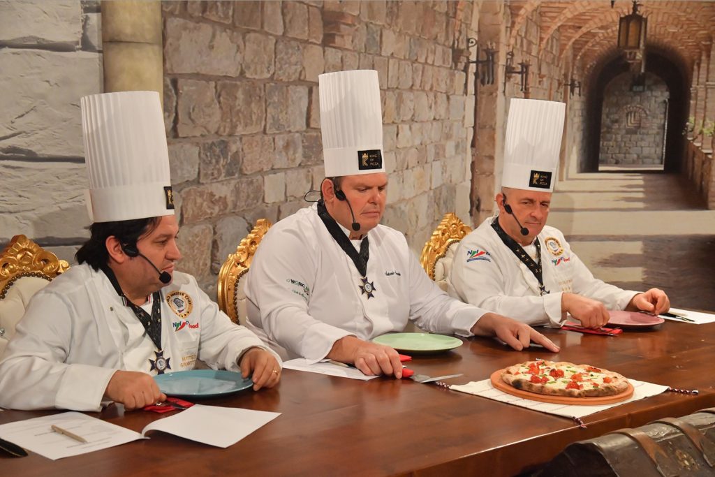 KING OF PIZZA - i tre giudici seduti ad un tavolo, vestiti con casacca bianca e cappello da cuoco
