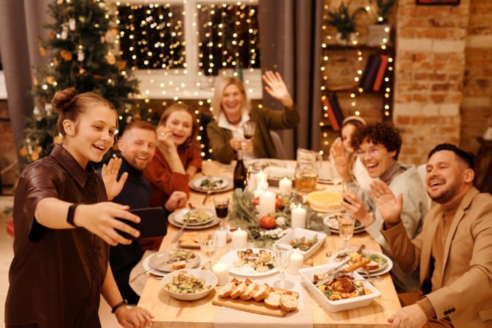Fegato, colesterolo, trigliceridi, disintossicazione. Tavola apparecchiata durante un pasto natalizio. Una famiglia seduta a tavola mentre si scatta un selfie.