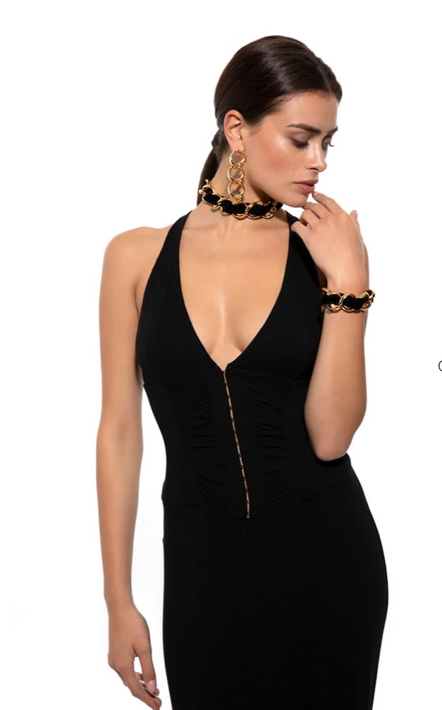 Gioielli De Liguoro - una modella vestita con un tubino nero molto scollato iindossa gioielli dorati intrecciati con un nastro di velluto nero ed ha un braccio lungo i l fianco e l'altro piegato e con la mano si sfiora il viso