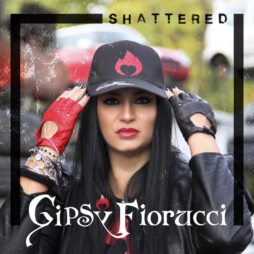 shattered - la copertina del singolo che ritrae gipsy fiorucci un primo piano, giubbotto di pelle nera, cappellino nero in testa , e guanti da auto tagliati sulle dita, uno rosso e uno nero