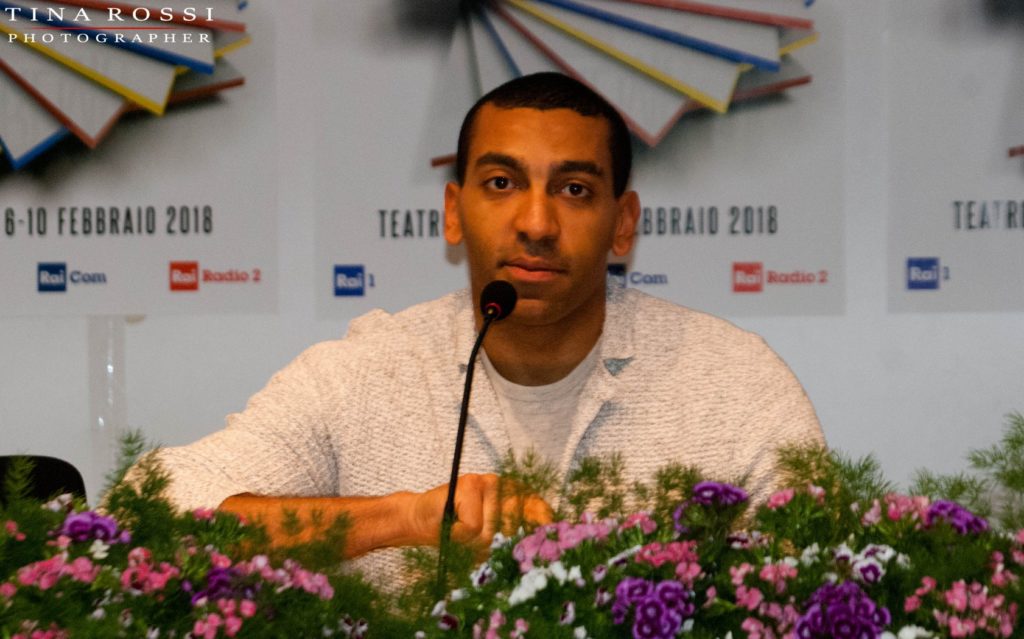 big sanremo 2022: mahmood in sala stampa al festival, seduto davanti a dei  fiori, indossa un maglione bianco