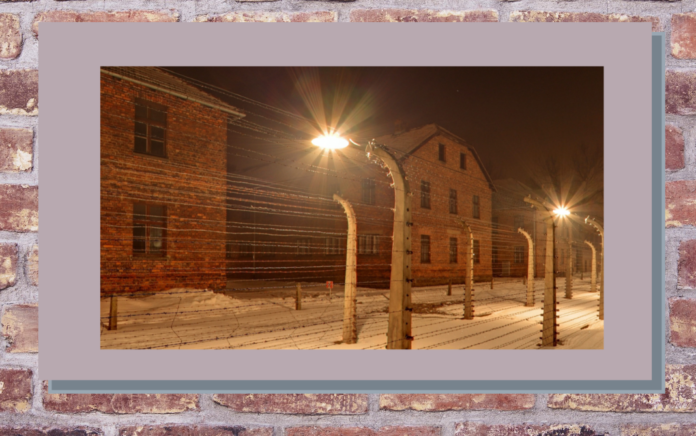 27 gennaio nella foto il capannone di un lager nazista con davanti una recinzione di filo spimnato e un lampione che illumina la notte buia
