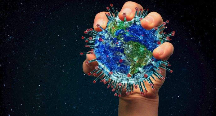 Una mano stringe con forza un globo terrestre fatto a forma di proteina spike del coronavirus