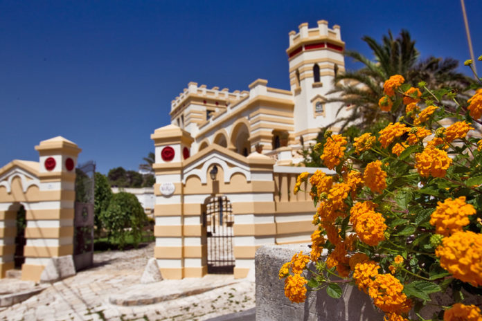 Villa Raffaella, puglia, turismo, salento, mare, santa cesarea terme. L'ingresso di Villa Raffaella, villa ottocentesca caratterizzata da colori giallo paglierino e bianco. In primo piano dei fiori di colore arancione.