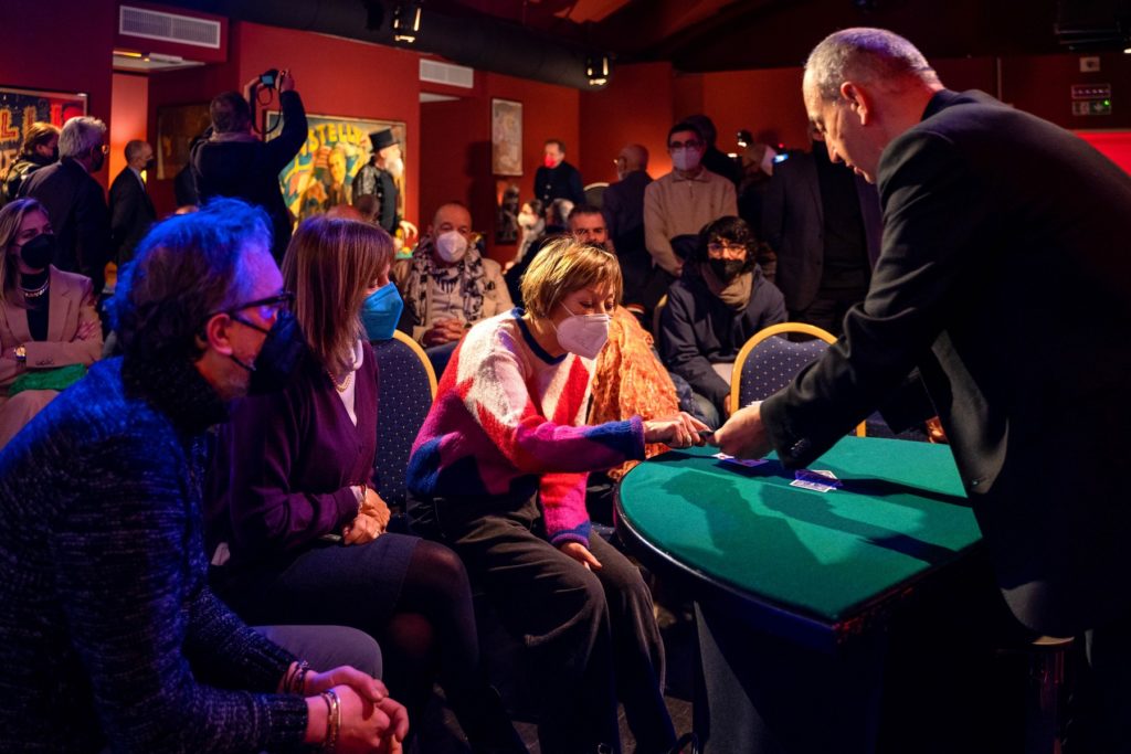 interno del Circolo Amici della magia di torino durante una perfomance tavolo verde con persone intorno mentre si effettua uno spettcolo con le carte